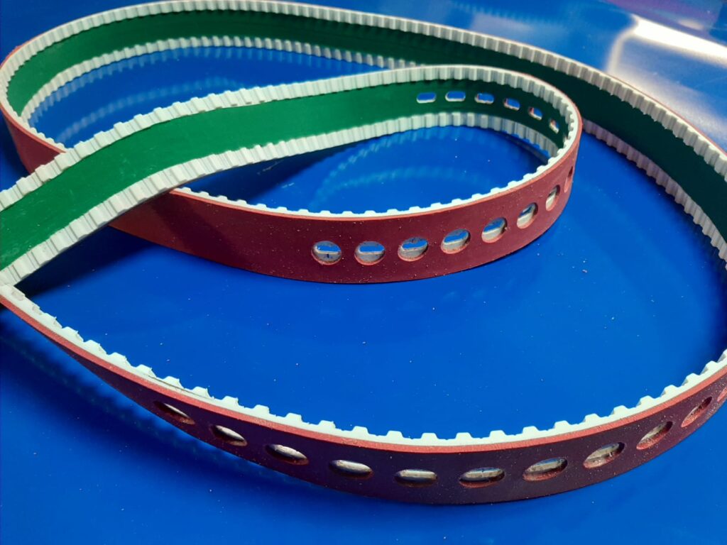 Texto alternativo (ALT) Correa dentada T10 con dientes mecanizados, tejido NFT en el rebaje del diente, recubrimiento Linatex y taladros para vacío, desarrollada para máquinas Serra de la industria del cartón.